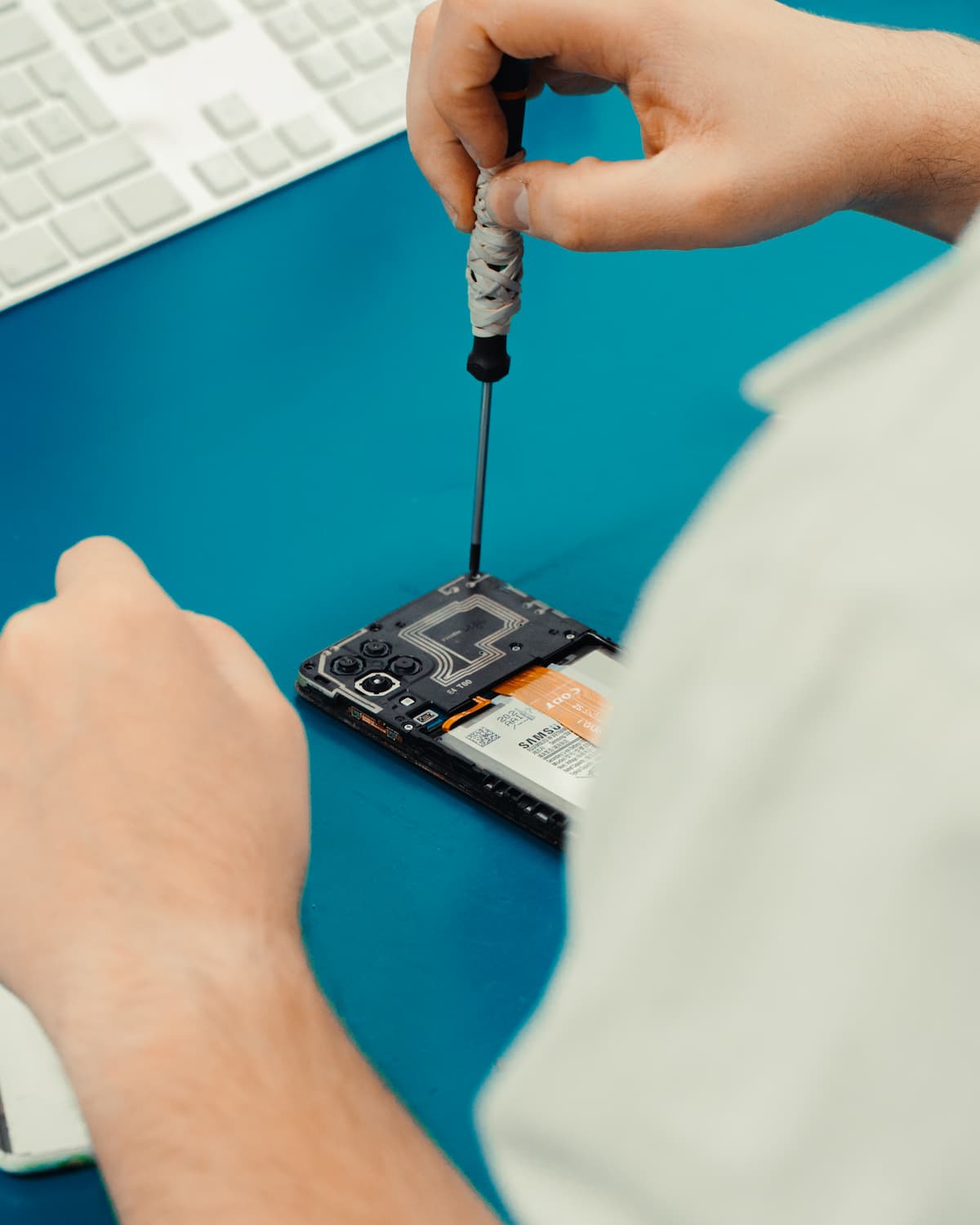 Técnico com uma chave a reparar um telemóvel